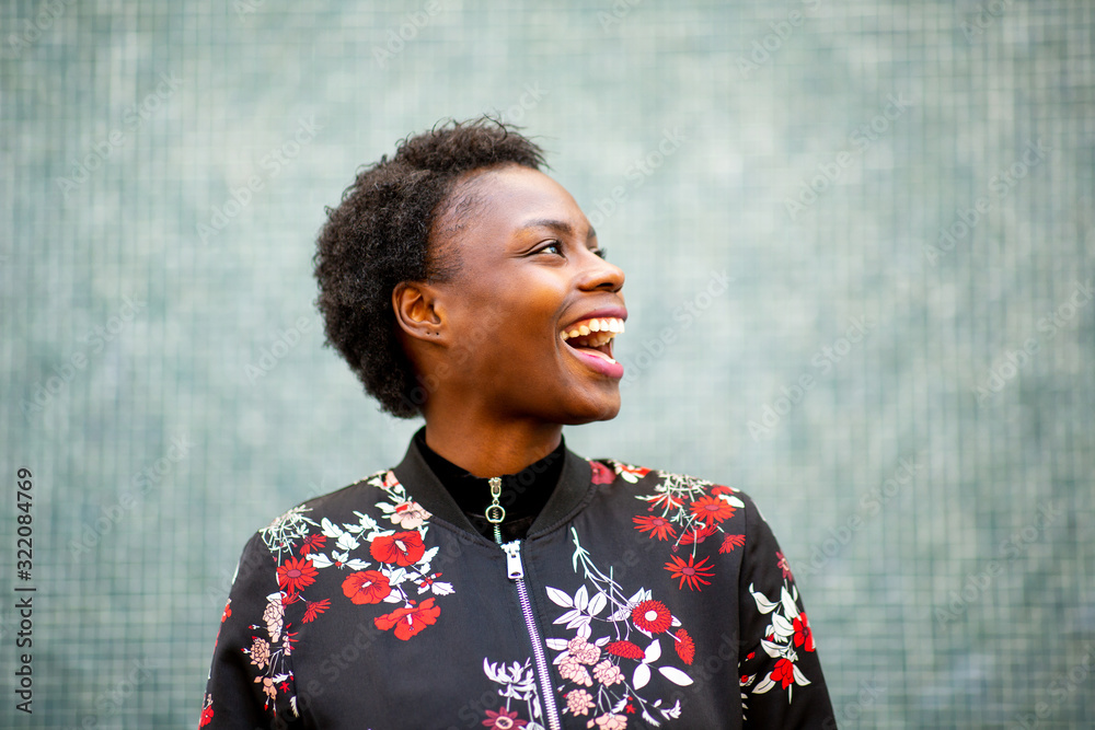 Wall mural Close up happy young african woman laughing and looking away