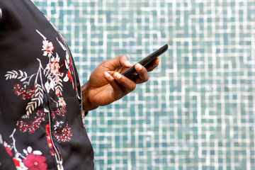 side of african woman hands holding cellphone outdoors