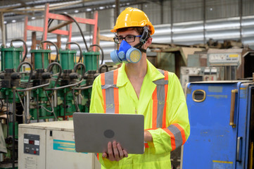 Caucasian male with protective mask with laptop working in factory area.