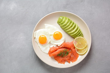 Healthy breakfast concept, fried eggs, avocado and smoked salmon, top view