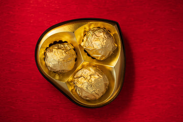 Premium Heart Shaped Chocolate Box Background. Valentine's day chocolate gift background with copy space. Heart shaped box full of luxury chocolate on red textured background.