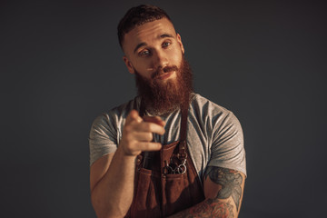 Bearded barber pointing at camera