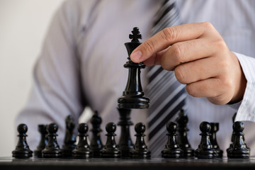 hand of businessman moving chess in competition, shows leadership, followers and business success strategies