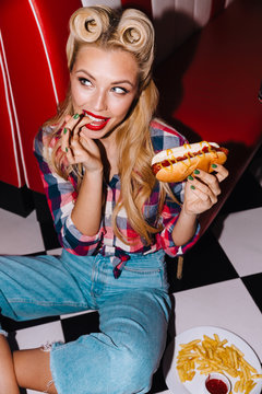 Photo of young excited woman eating hotdog and french fries