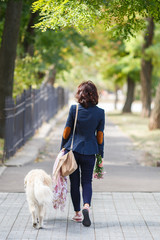 Beauty woman with her dog playing outdoors. Woman walking Labrador Retriever in park. Girl with dog on the street