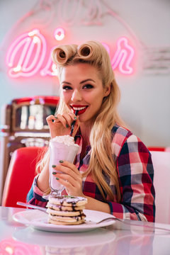 Photo of gorgeous cheerful woman eating pancakes and drinking milkshake
