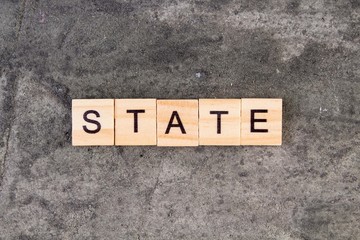 States word written on wood block, on gray concrete background. Top view.