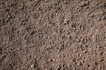 Brown plowed soil on sunlight background