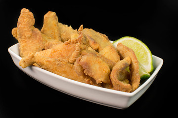 Fried Tilapia strips in platter  isolated in black background