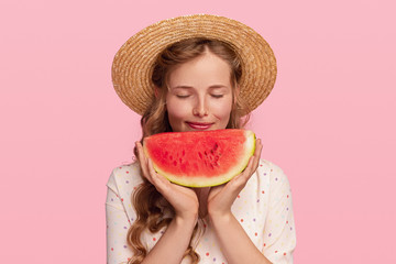 Pleased woman smelling fresh watermelon