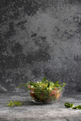 Citrus, vegetarian (vegan) salad: pea sprouts, sunflower, lettuce, grapefruit, olive oil in a glass bowl on a gray concrete background back space, concept