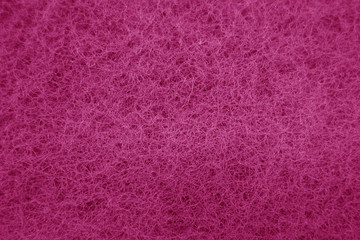 Cleaning sponge rubbing surface close up with blue effect in pink tone.