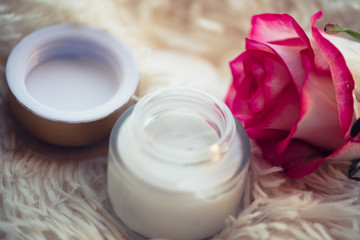 Fototapeta na wymiar Skincare concept. cream in a glass jar with an open lid and a rose