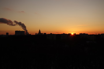 Fototapeta na wymiar Sunset with a plume of smoke in black and orange in Moscow in winter