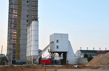 Obraz premium Ready mix stationary concrete batching plant on construction site. Producing сoncrete and portland cement mortar for construction industry. Constructing a new building
