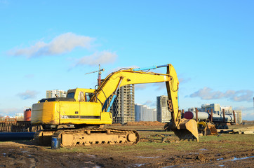 Obraz premium Excavator digs ground at a construction site for installing concrete storm pipes. Backhoe the digging pipeline ditch. Commercial and Public Civil Work Contracting, trenching, tamps soil