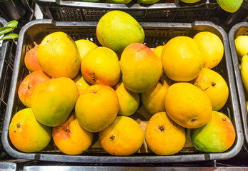 Exotic tropical fruits in the asian market. Fresh ripe sweet mangoes. Yellow, orange mango. Healthy vegan raw food in the shop, store in containers