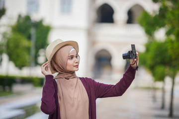 Portrait of beautiful young solo Muslim traveler taking self photo (selfie)