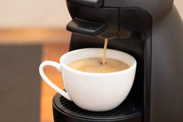 Making coffee in a capsule machine. Fragrant hot drink is poured into a cup. Real yummy home making.