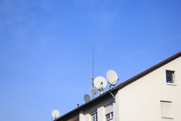 Fototapeta na wymiar Parabolspiegel und Fernsehantenne auf einem Hausdach