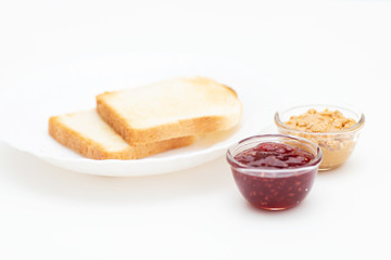 American breakfast. Toasted toasts, peanut butter and raspberry jam on a white plate. Sandwich Ingredients.