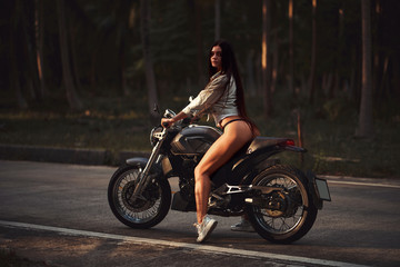 Plakat Sexy fit woman with a black motorcycle in cafe racer style