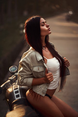 Fototapeta na wymiar Sexy fit woman with a black motorcycle in cafe racer style