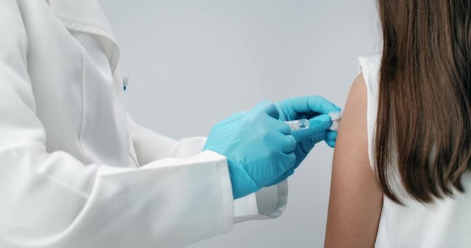 Medical worker in protective gloves making injection in girl's hand, disease prevention, vaccination