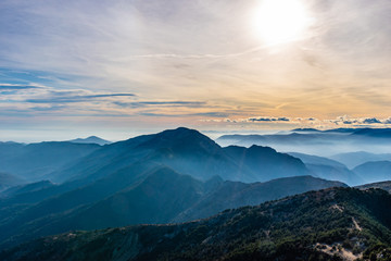 Beautiful captivating landscape of the layered misty hazy French Alps mountain range in Alpes-Maritimes in the afternoon during a sunny day