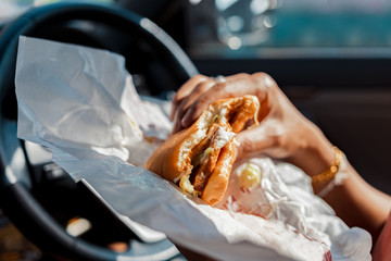Man eating hamburger in car.