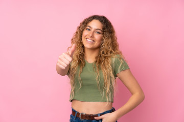 Young blonde woman with curly hair isolated on pink background with thumbs up because something good has happened