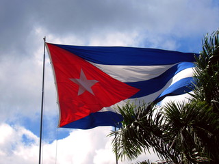 National flag of Cuba on flagpole in front of blue sky.