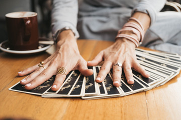 Woman is reading Tarot cards on the table in cafe