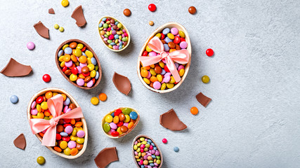 Chocolate Easter eggs and candy on concrete table, festive Easter background flat lay, copy space. Easter card with traditional Easter treats on grey table top. Sweet Easter concept