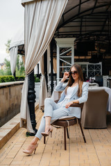 A beautiful young girl is sitting on the veranda of a beautiful house. Relaxation.