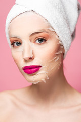 naked girl in moisturizing face mask looking at camera isolated on pink