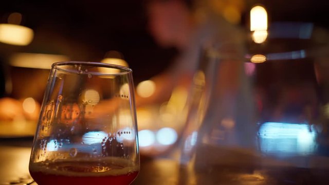 beer glass on table in bar. bartender on blurred background