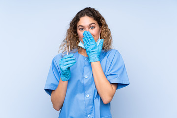 Young blonde woman dentist holding tools isolated on blue background with surprise facial expression