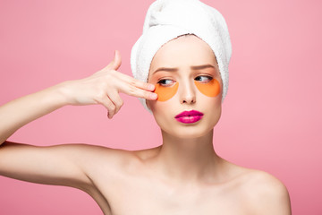 naked girl touching face with eye patches isolated on pink