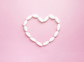 Heart shape made from pills for therapy, concept of treatment and health care on soft pink