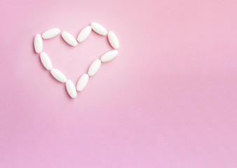 Heart shape made from pills for therapy, concept of treatment and health care on pink