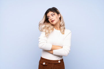 Young teenager girl over isolated blue background making doubts gesture while lifting the shoulders