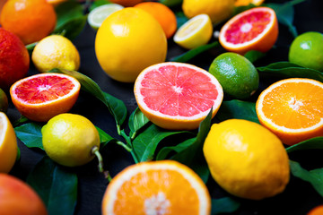 Bunte Zitrusfrüchte mit Orangen, Zitronen, Pink Grapefruit und Limetten auf schwarzem Schiefer Hintergrund