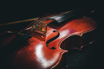 Fototapeta premium An old violin lies on a table against a dark background.