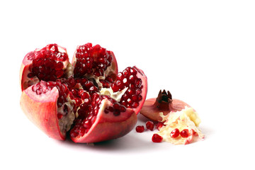Ripe pomegranate fruit isolated on white background cutout. Pomegranate seeds. Pieces of pomegranate are scattered. Horizontal orientation. Copy space for text.