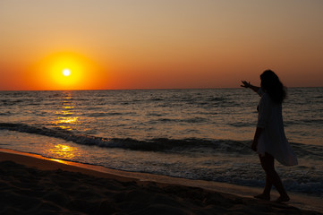 Fototapeta premium Girl walks along the coast at sunset, sunrise