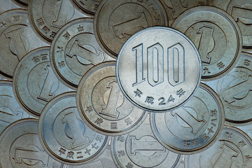 A field of Japanese coins in 1 yen, on it lies a coin of 100 yen. News about the economy, finances and interest rate of the central bank of Japan. Deposits and loans. Macro