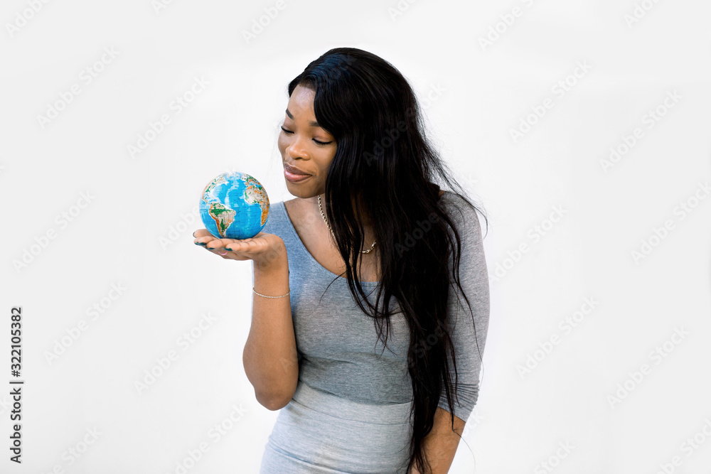 Wall mural pretty young african american woman teacher or student looking at world earth globe holding it in th