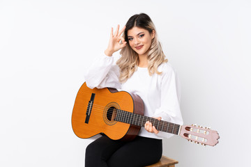 Obraz premium Teenager girl with guitar over isolated white background showing ok sign with fingers