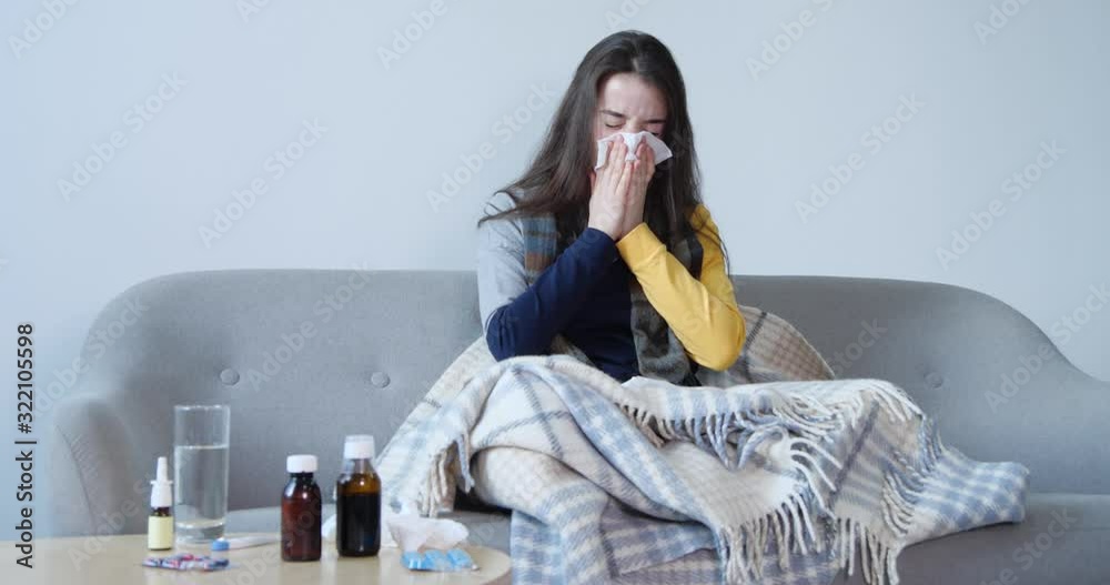 Wall mural Young woman suffering from cold on sofa at home